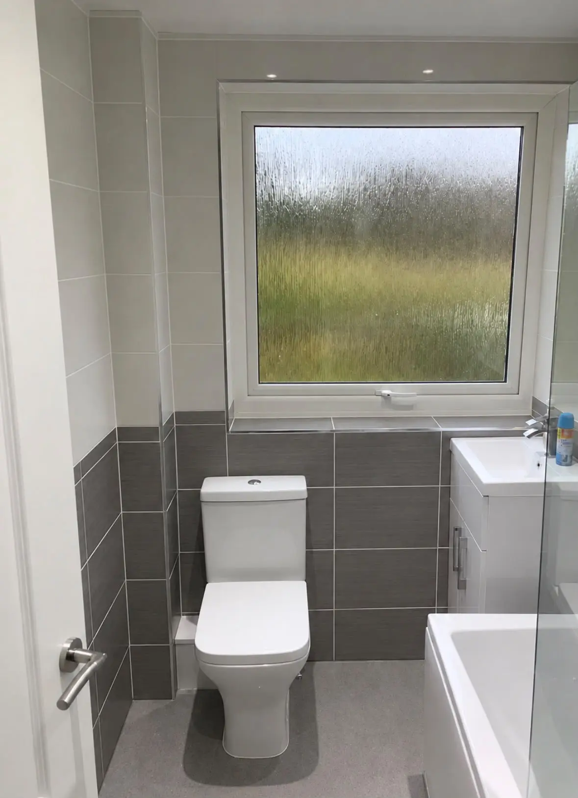 Close-coupled WC beneath an obscure-glazed window, with grey band tiling