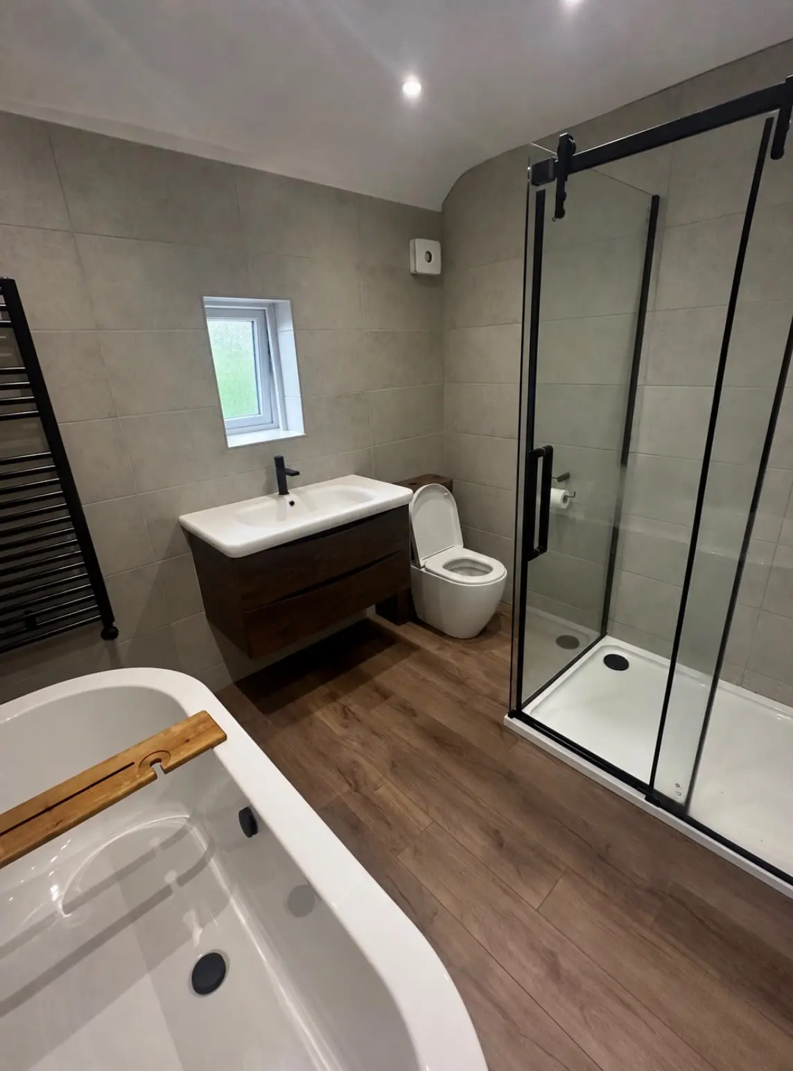 The finished bathroom: freestanding bath, vanity, WC and walk-in shower on oak LVT