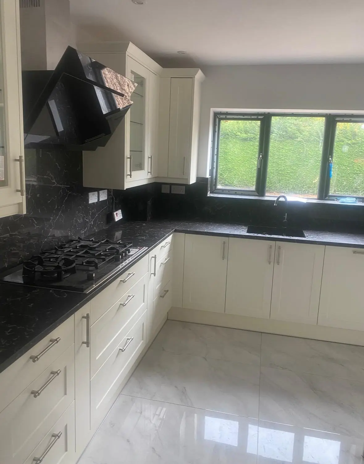 Cream shaker run with a gas hob, angled black extractor and glazed wall cabinets