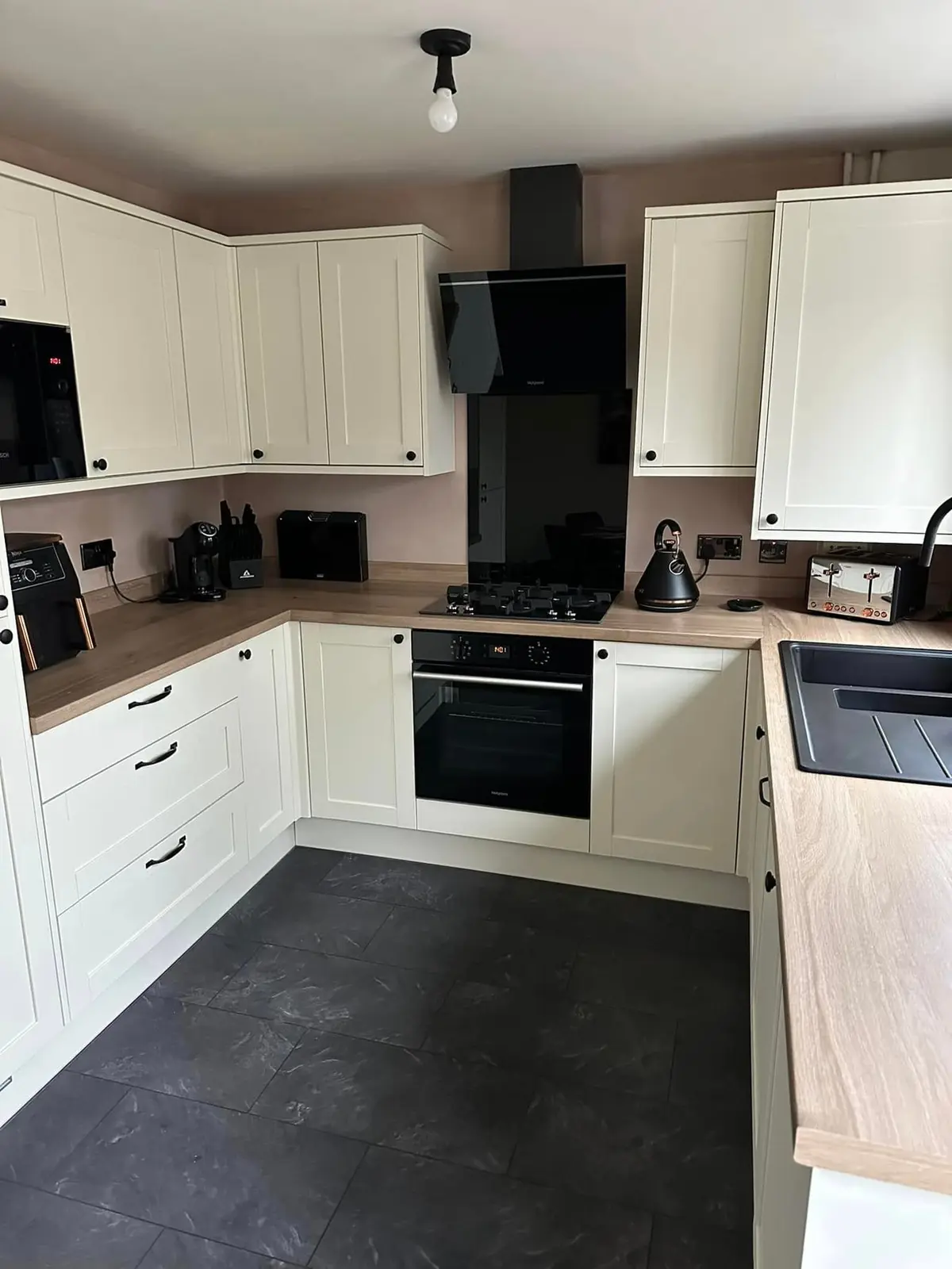Cream shaker kitchen run beneath the window with a black sink