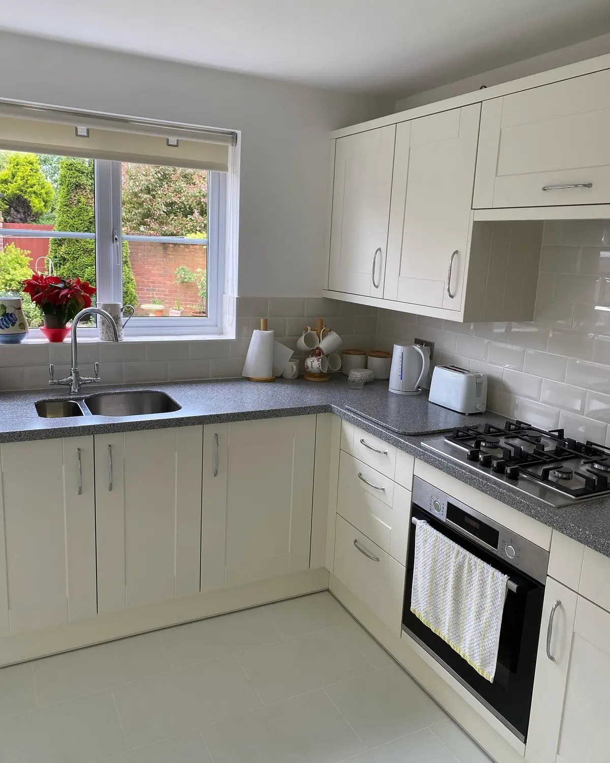 Cream shaker kitchen with gas hob, grey quartz worktop and white metro tiles