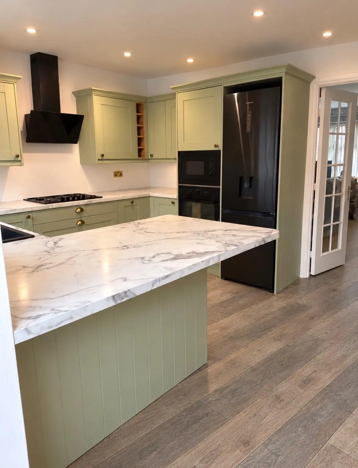 Forest green shaker kitchen with Carrara laminate worktops, a black extractor and a black American fridge freezer