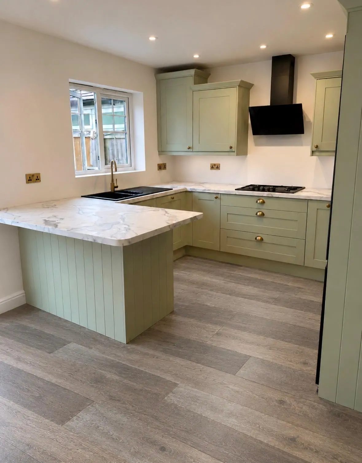 Forest green shaker run beneath the window, with a Carrara laminate peninsula