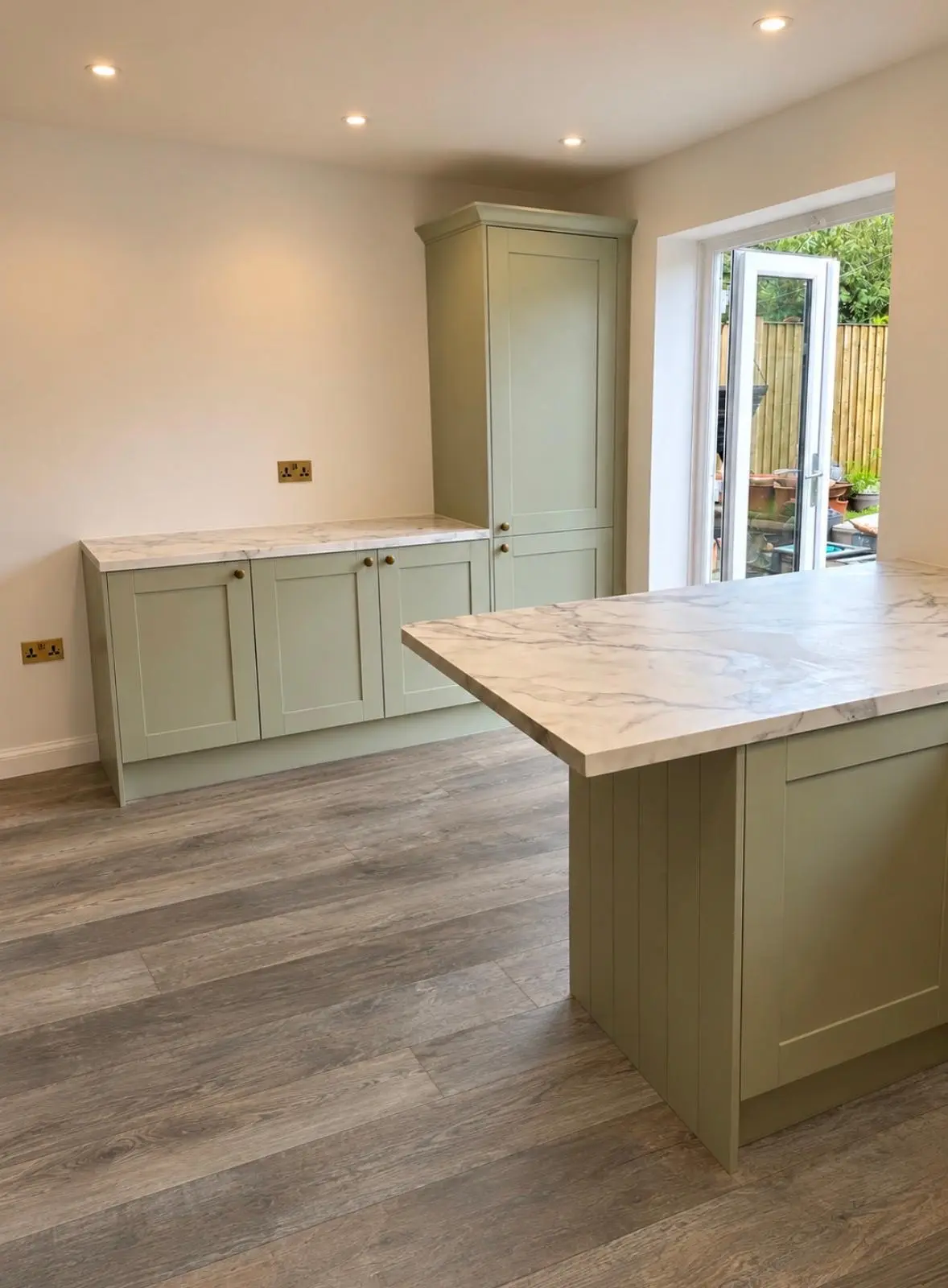 Forest green tall unit and peninsula, with glazed doors to the garden