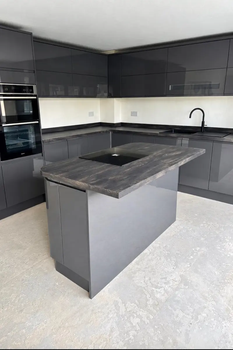 Graphite gloss island with induction hob in front of the sink run