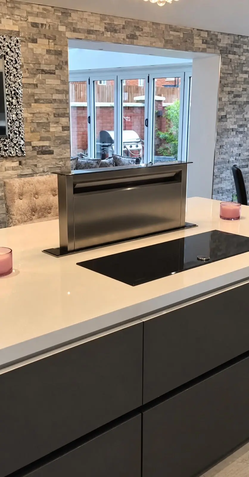 Downdraft extractor rising from the island behind the induction hob