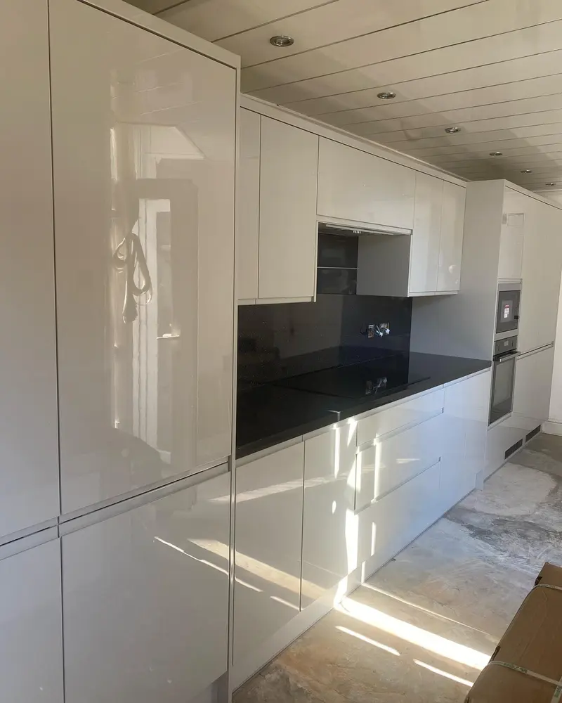 White high-gloss handleless units and tall housing installed on day one, with black worktops