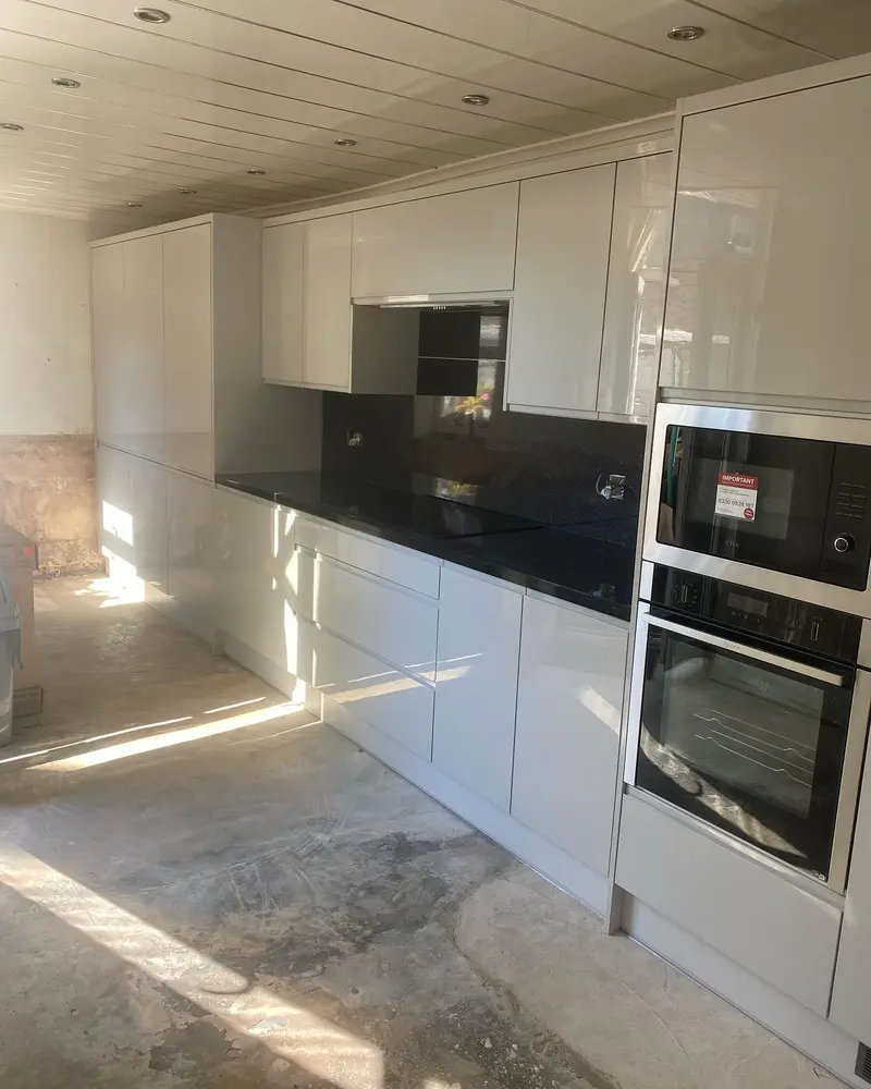 White gloss kitchen run on install day, seen down the length of the room