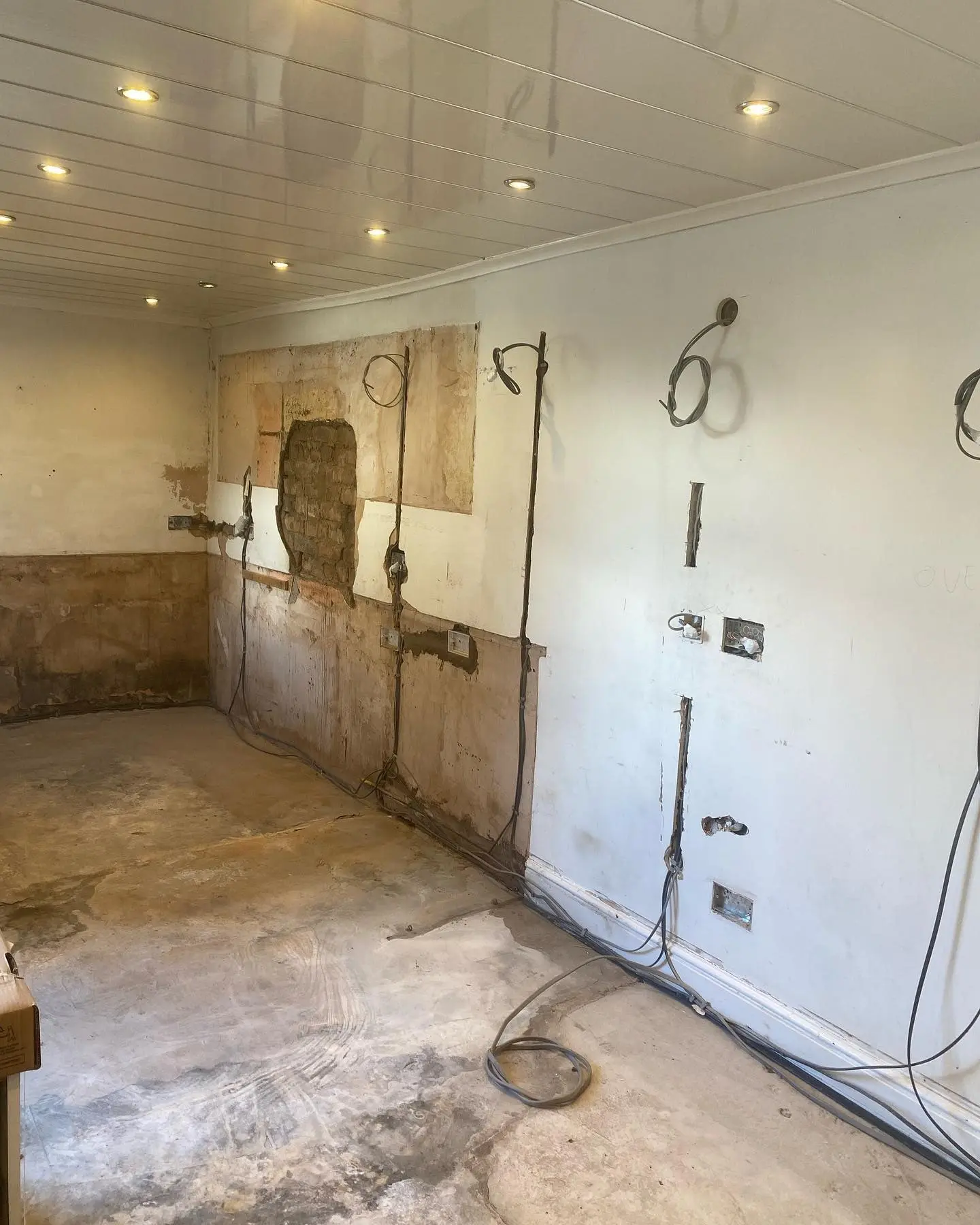 Kitchen stripped back with first-fix electrics run along the walls and a panelled ceiling with downlights