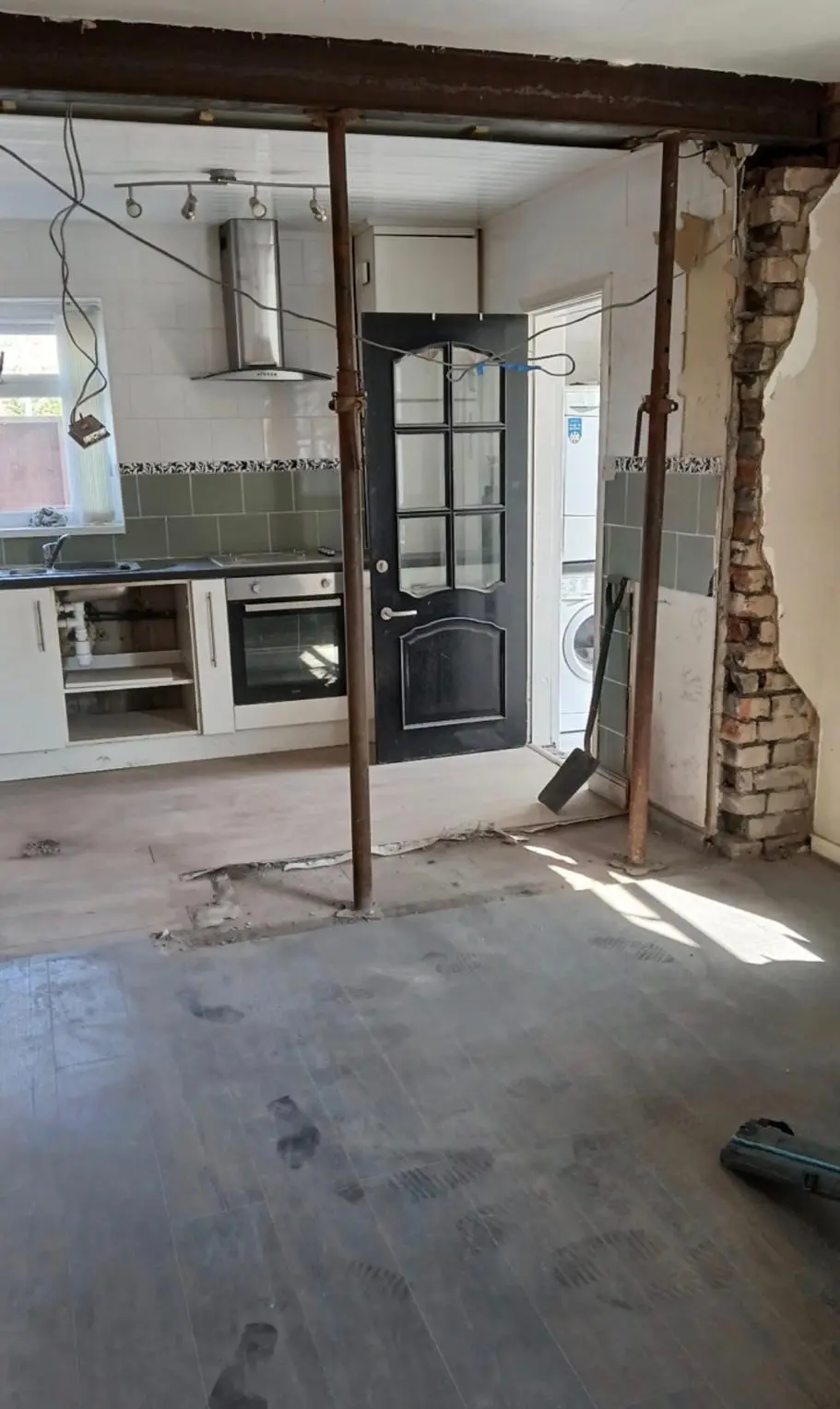 The load-bearing wall taken out, with temporary props under the new steel and the old kitchen beyond