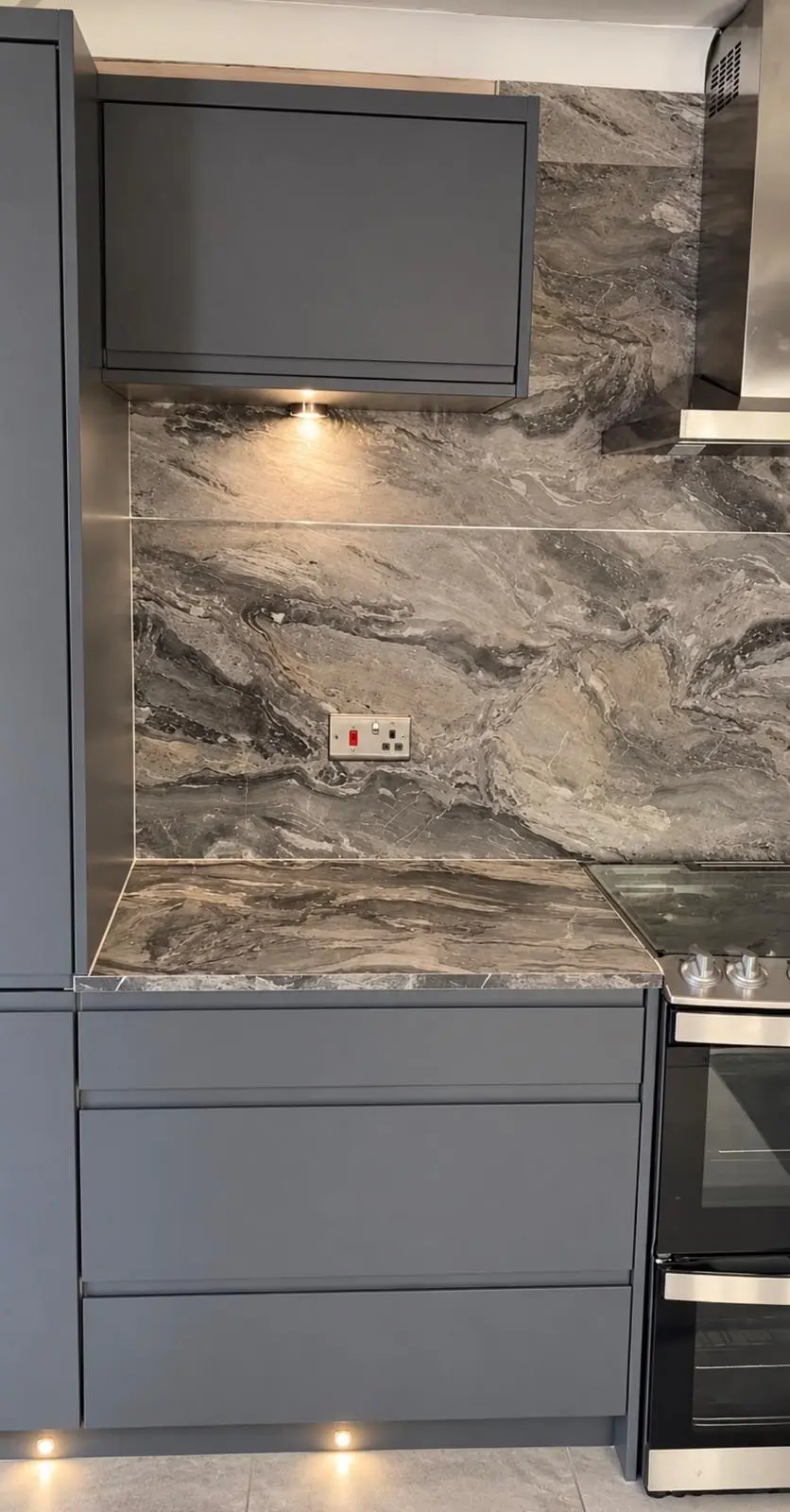 Lava grey wall unit over a marble-effect worktop and matching wall panel, lit from below