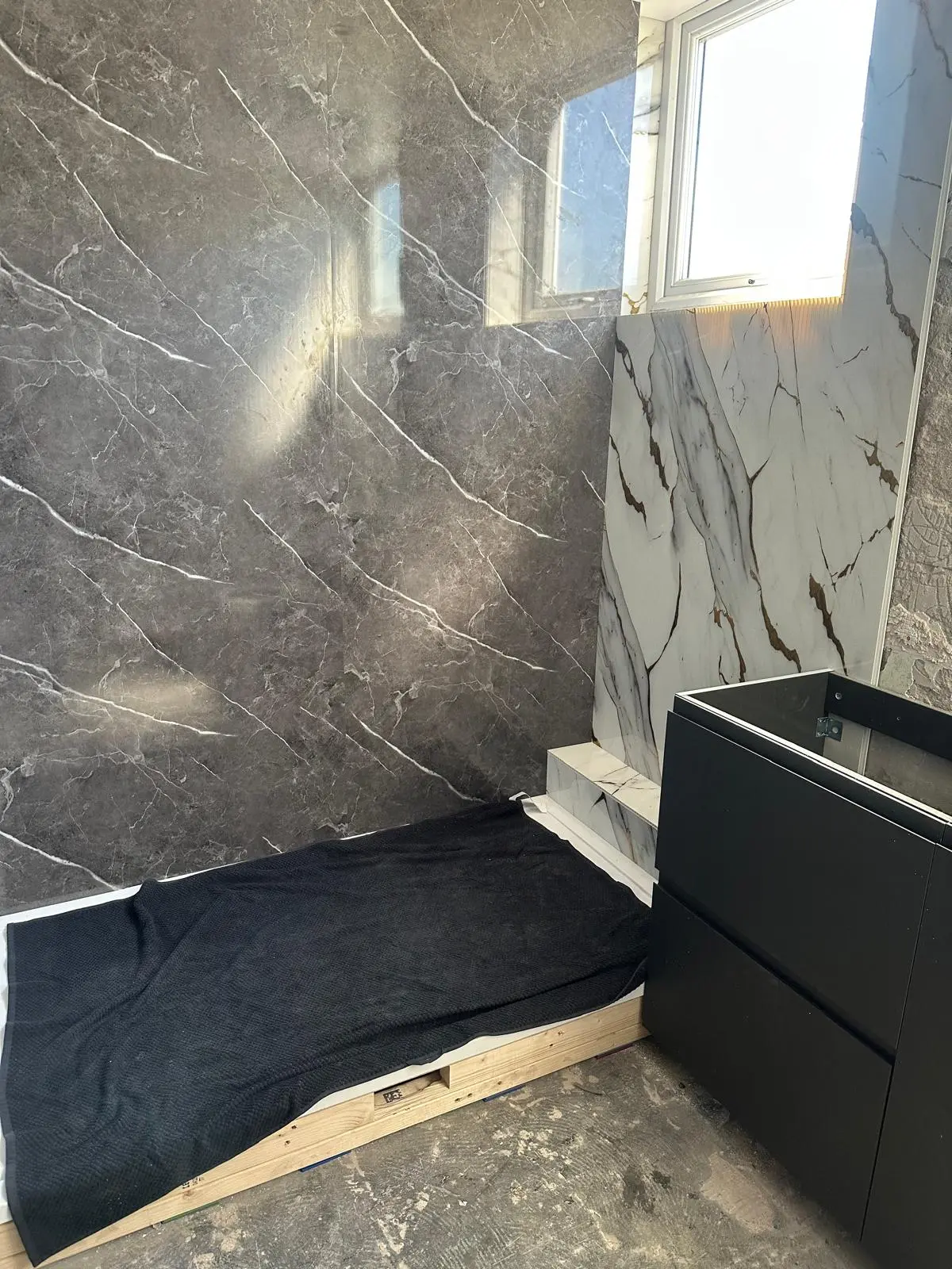 Shower area being prepared beside a black vanity unit
