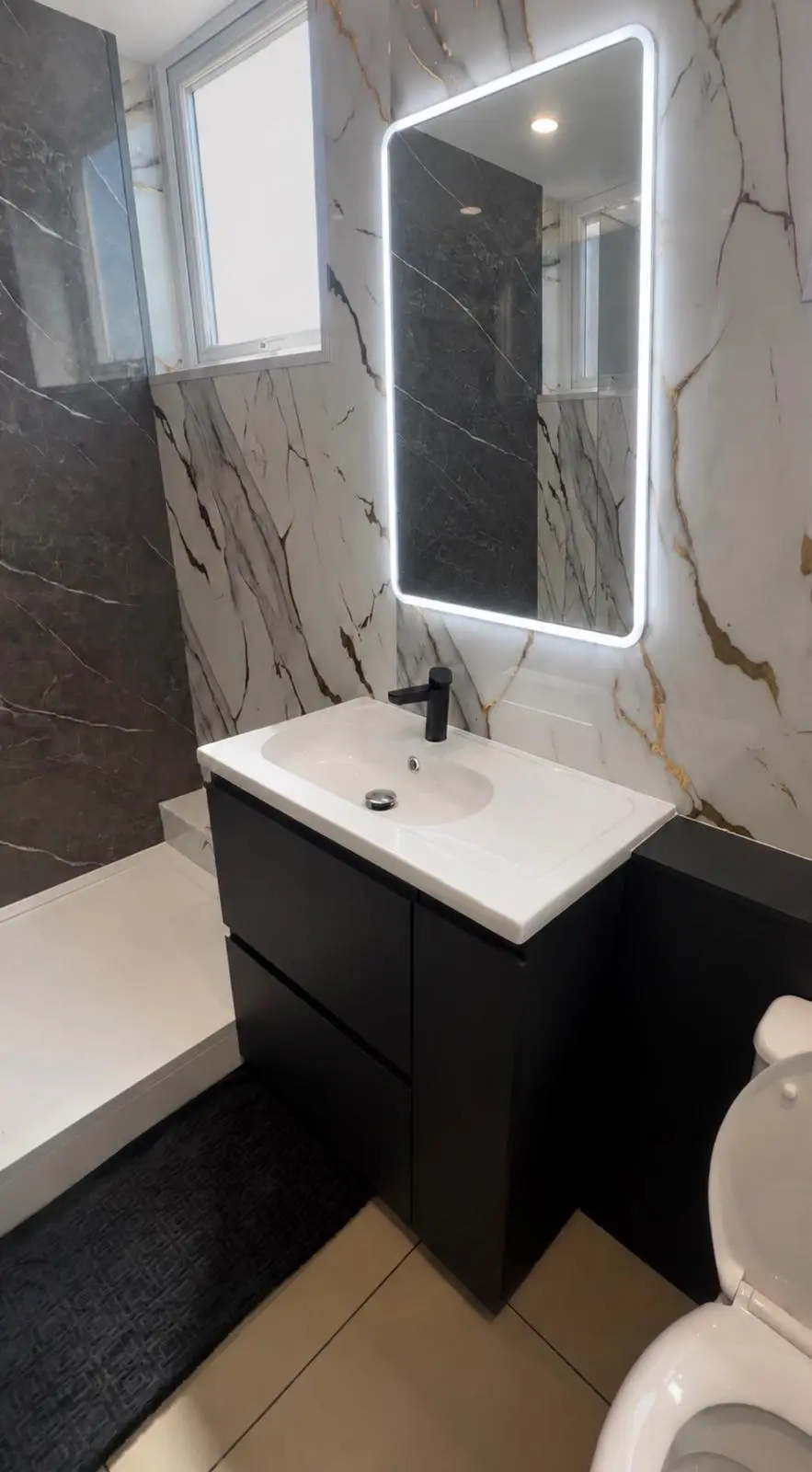 Black vanity unit with a black tap and illuminated mirror