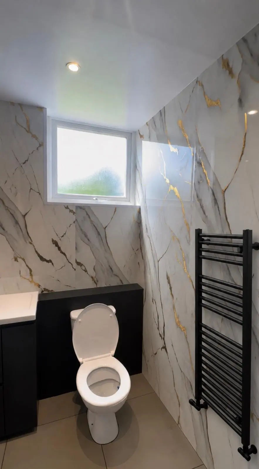 WC beneath the window, beside a black towel radiator