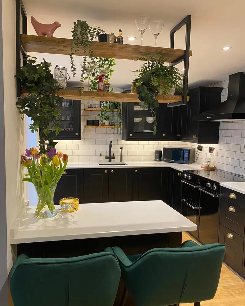 Matt black shaker kitchen with white quartz worktops, white metro tiles and suspended timber shelving with plants