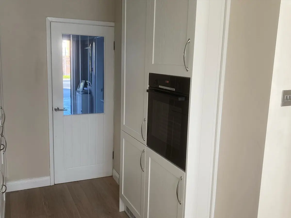 Light shaker tall housing with built-in oven beside a glazed door