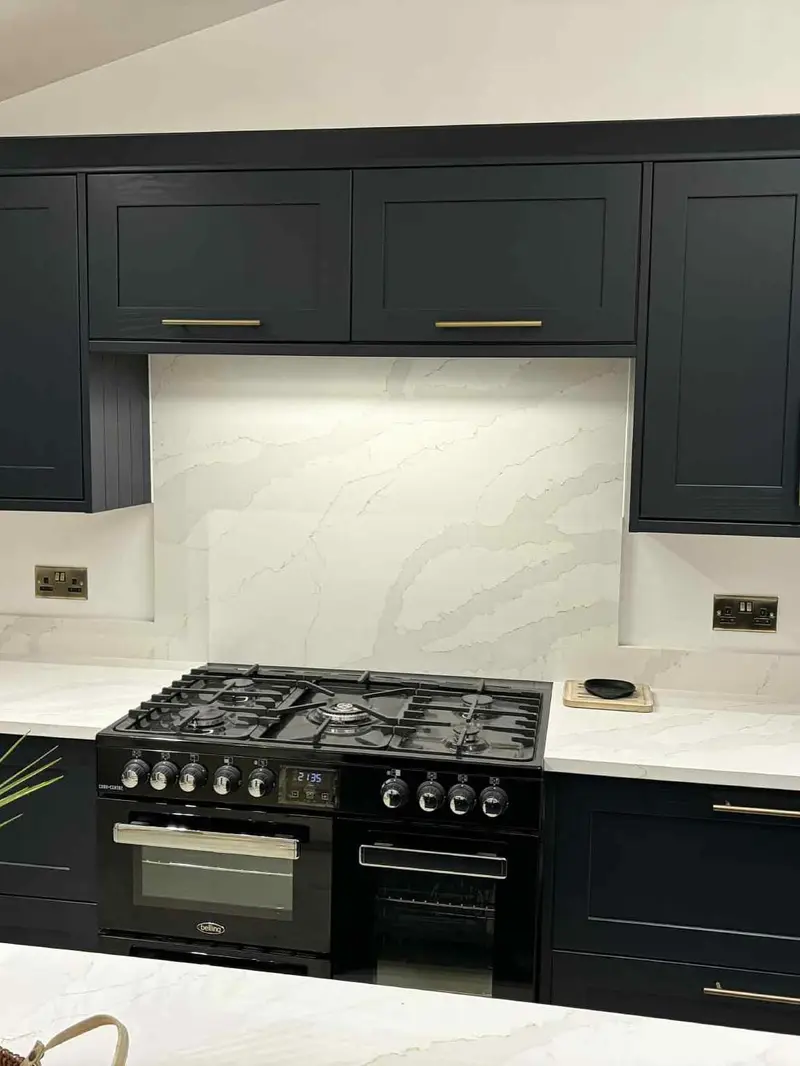 Navy shaker wall units framing a black range cooker and full-height splashback