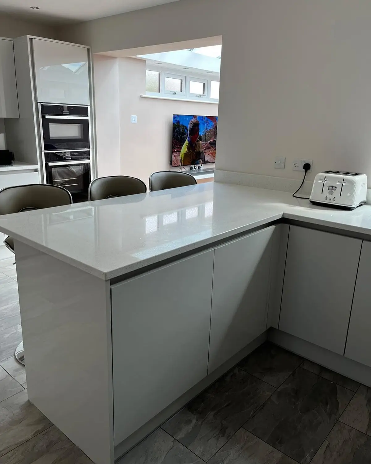 Handleless kitchen and peninsula seen from the living area