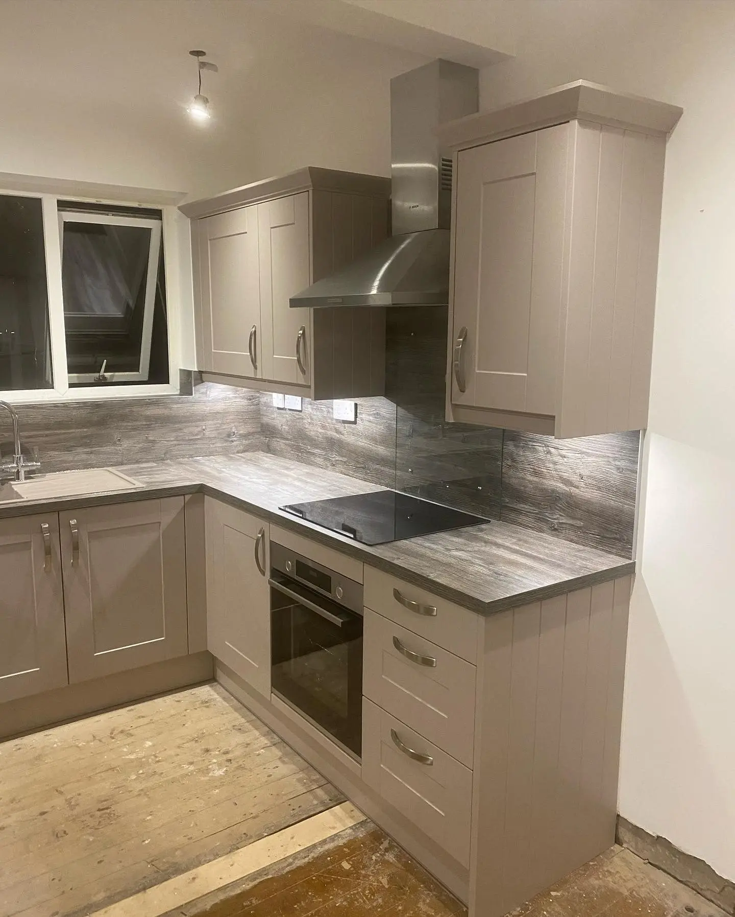 Pebble shaker U-shaped kitchen with worktop-matched wall panels instead of tiles