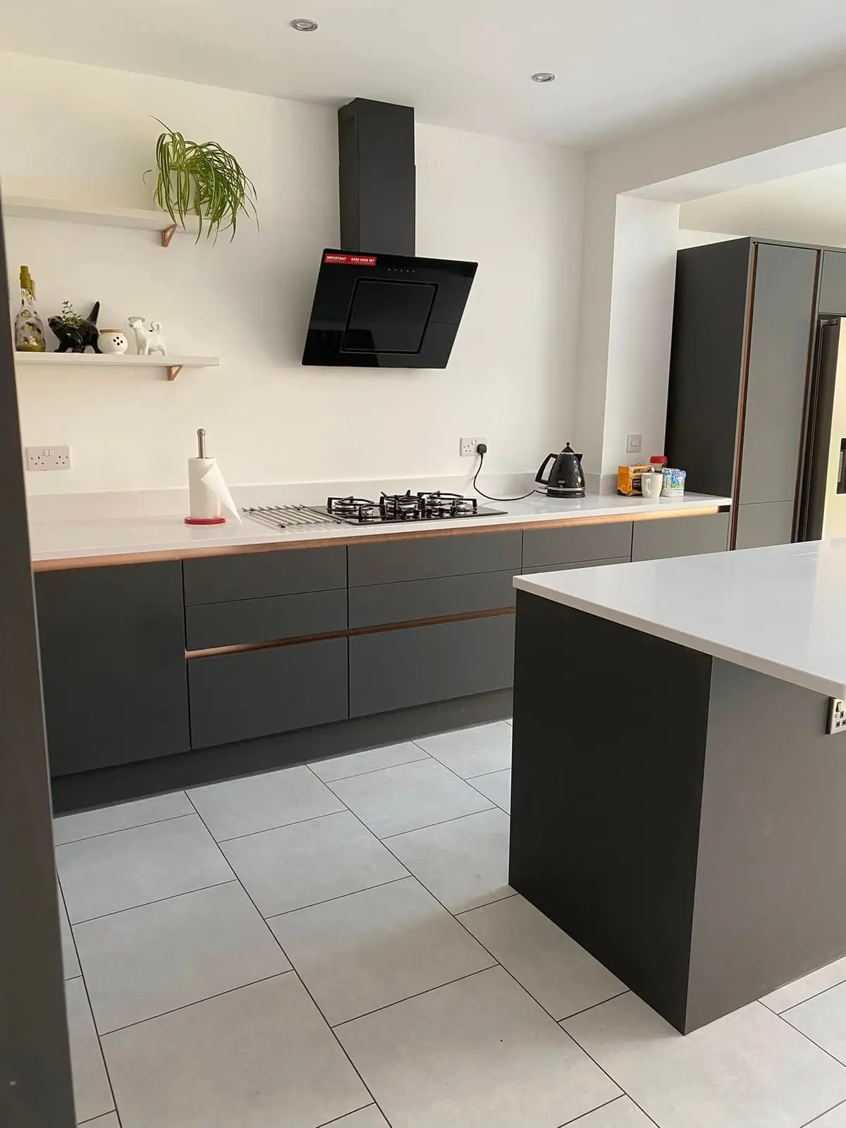 Dark grey base run with gas hob, black angled extractor, white worktop and open shelves