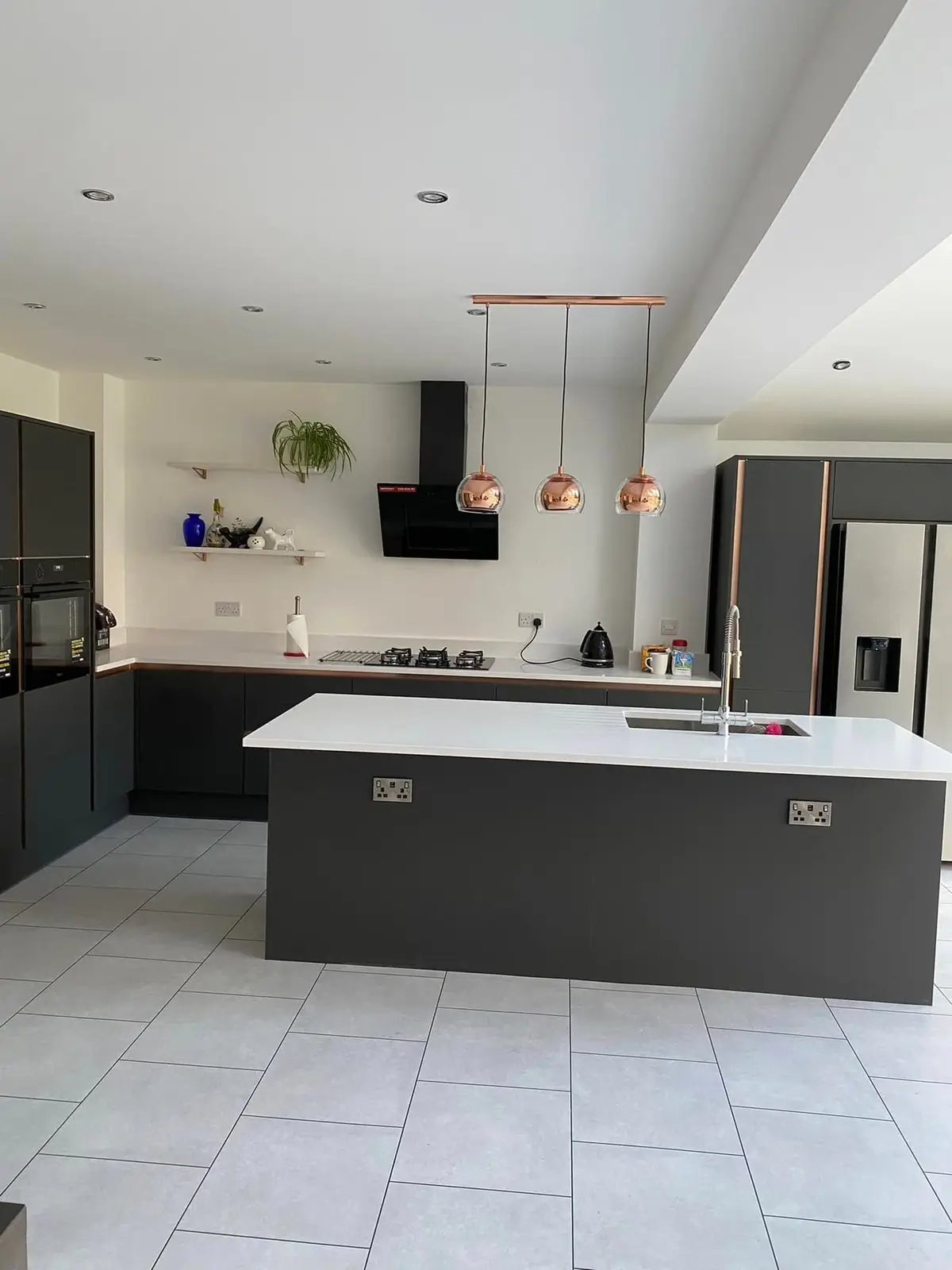 Vaulted kitchen extension with a dark grey island and copper pendants, seen from the far end