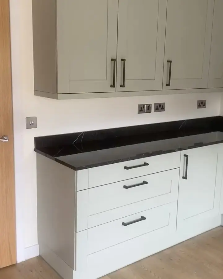 Sage green shaker base units with dark worktop and black handles