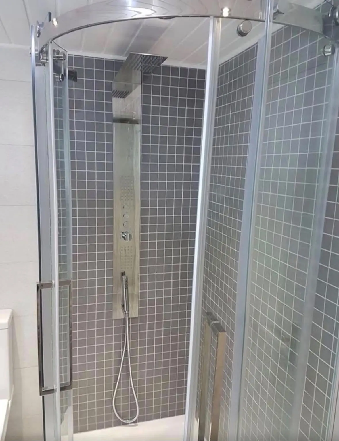 Quadrant shower enclosure with a shower tower panel and grey mosaic tiling