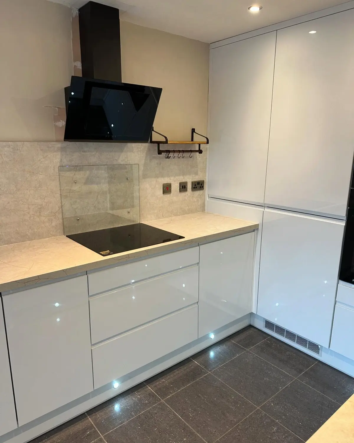 White gloss kitchen with black angled extractor and induction hob