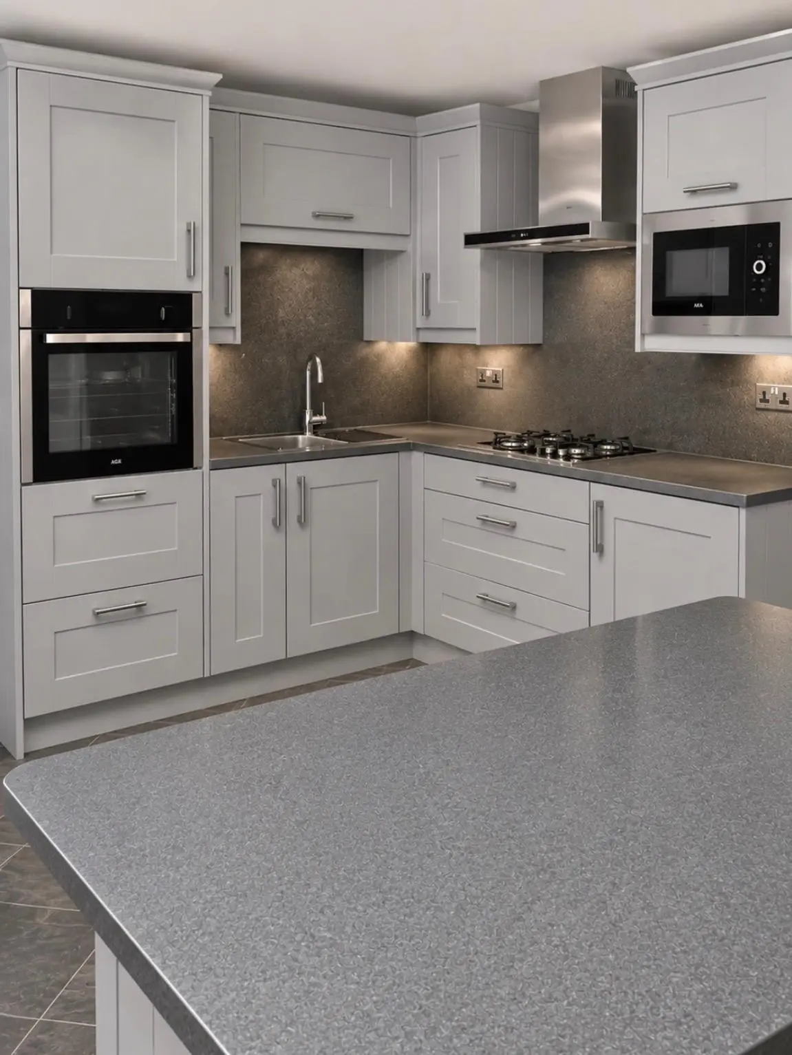 White shaker kitchen with grey sparkle worktops, matching wall panels, built-in oven and microwave, and the island in the foreground