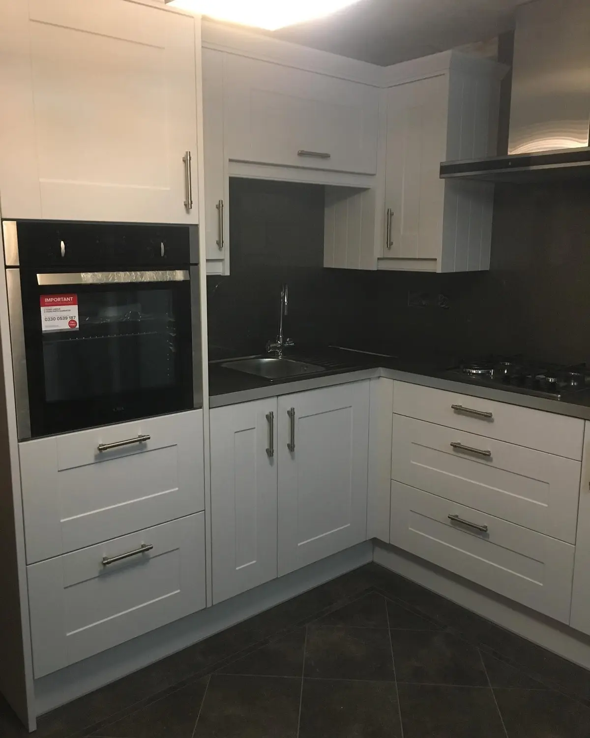 White shaker kitchen with built-in oven, chimney extractor and dark wall panels