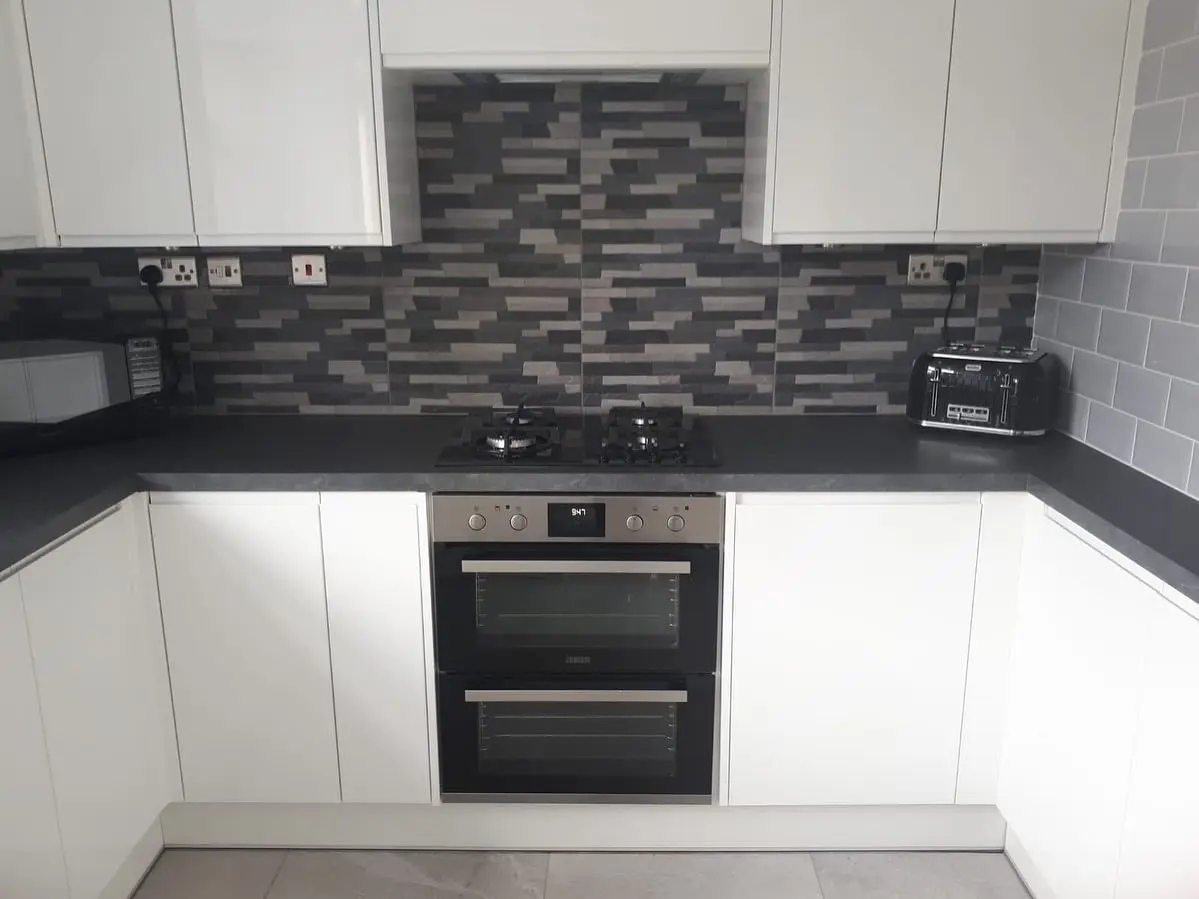 Finished white handleless kitchen with built-under double oven and mosaic splashback