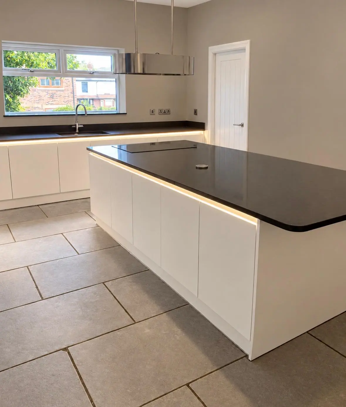 White handleless island with black quartz worktop, seen across the room