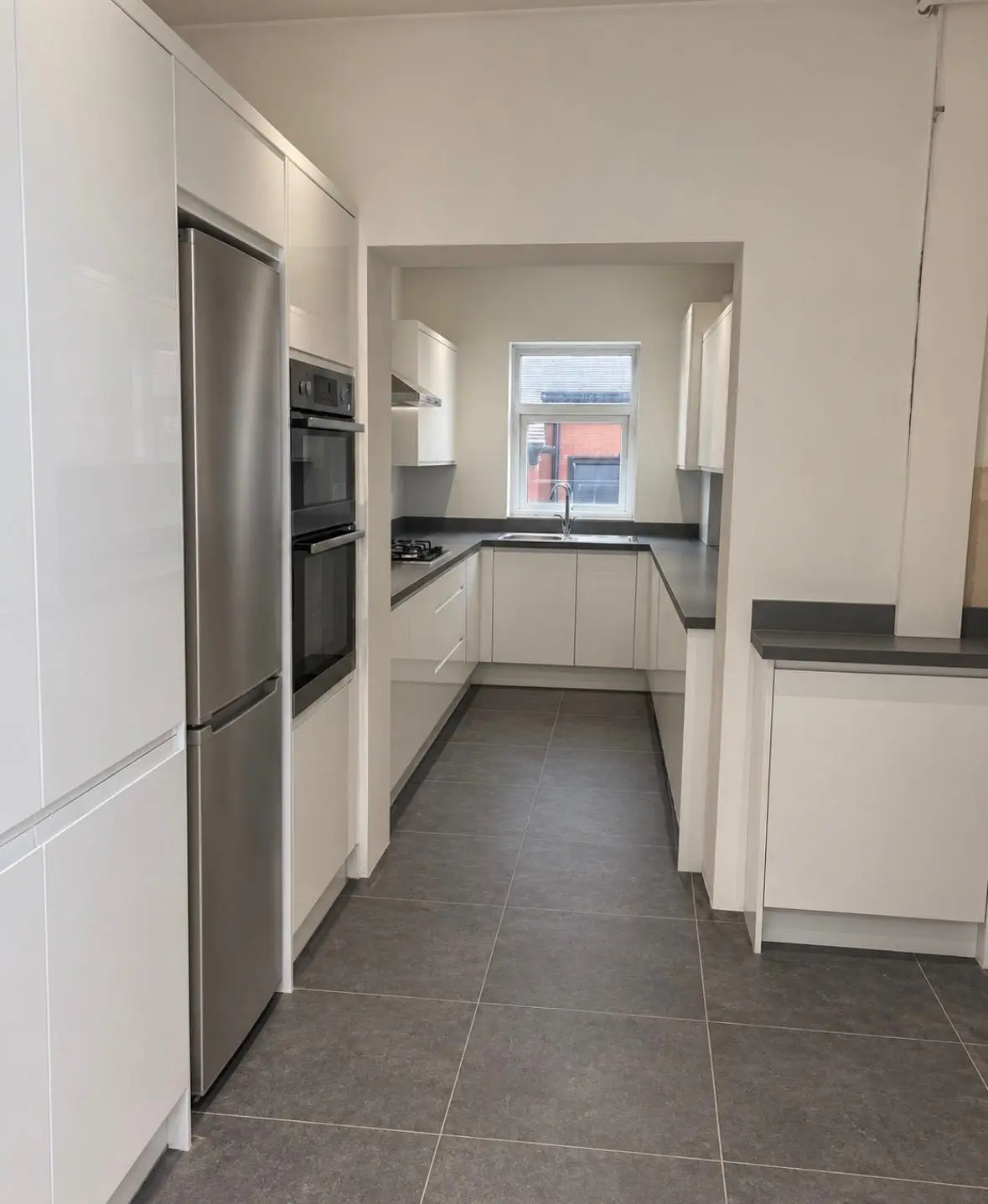White J-pull handleless kitchen with grey sparkle worktops, seen down the length of the room