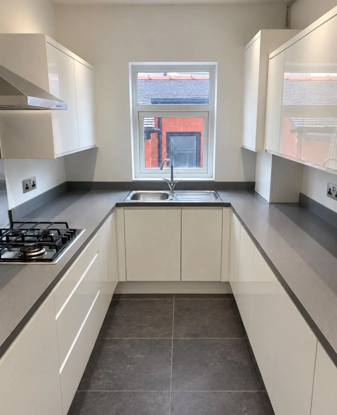U-shaped white handleless kitchen with grey sparkle worktops and upstands