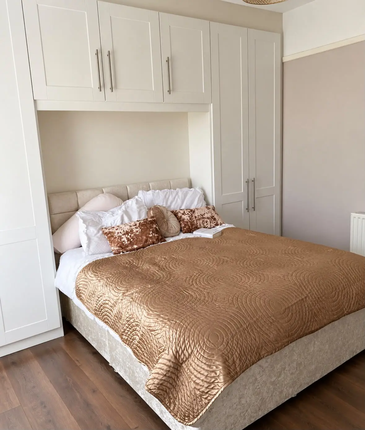 White shaker fitted bedroom with tall wardrobes either side of the bed and overhead bridging units