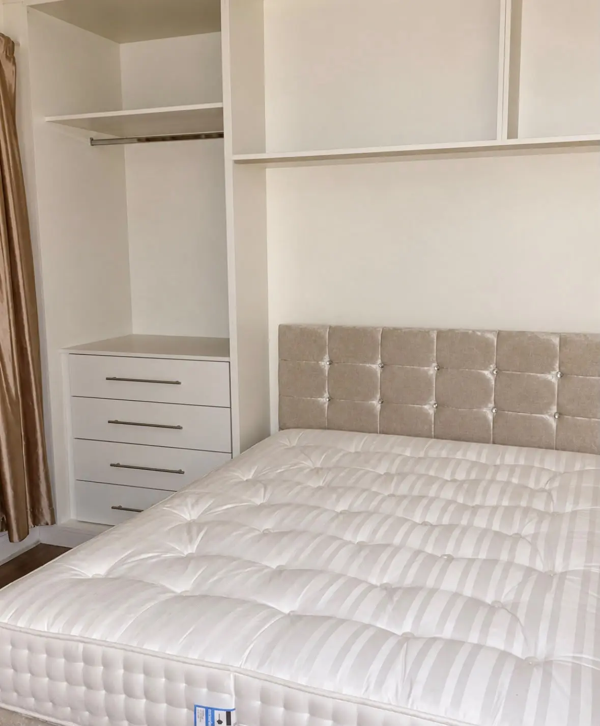 Open wardrobe interiors with a hanging rail and drawers beside the upholstered headboard